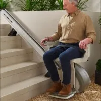 nicely dressed handsome older man on outdoor stair lift smiling