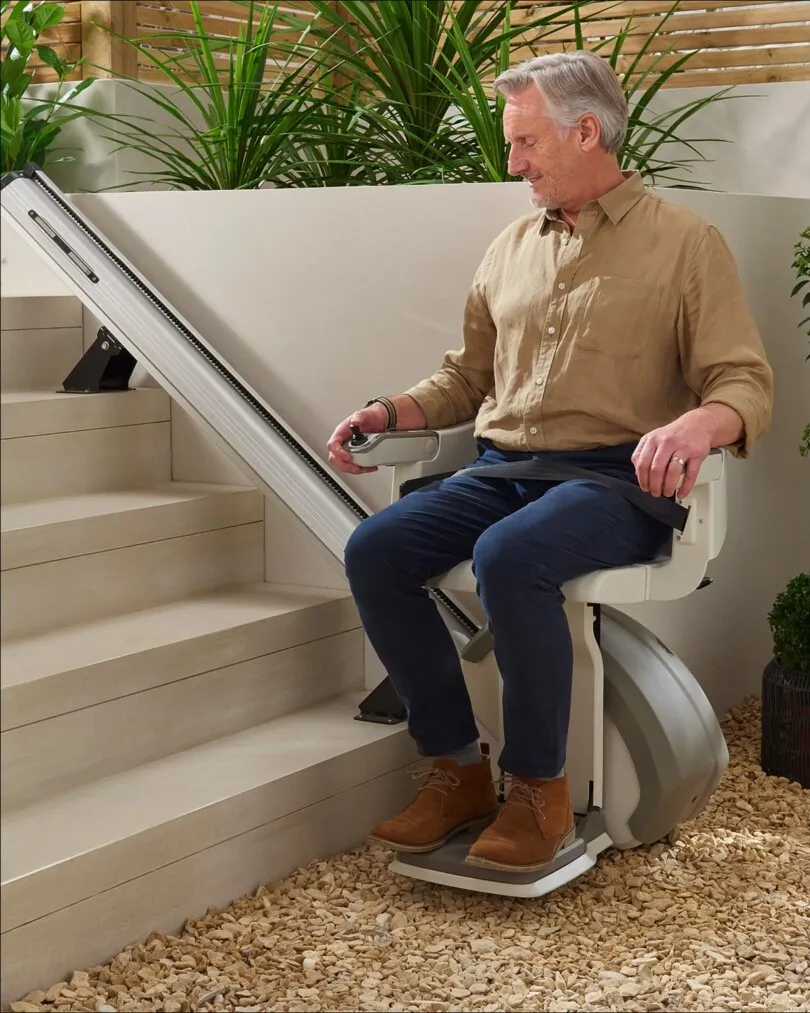 nicely dressed handsome older man on outdoor stair lift smiling