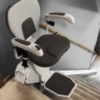 Black and white straight stair lift at the top of a staircase.