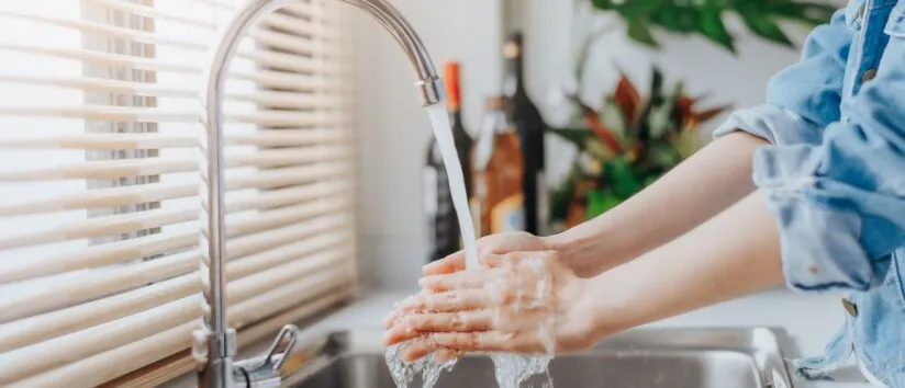 Person washing their hands in a kitchen sink.