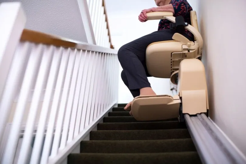Woman using a stair lift inside of her home.