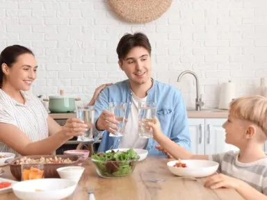 A young family drinking water at dinner