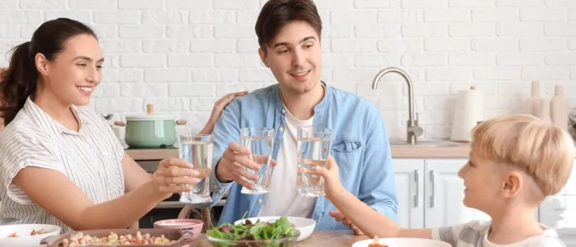 A young family drinking water at dinner