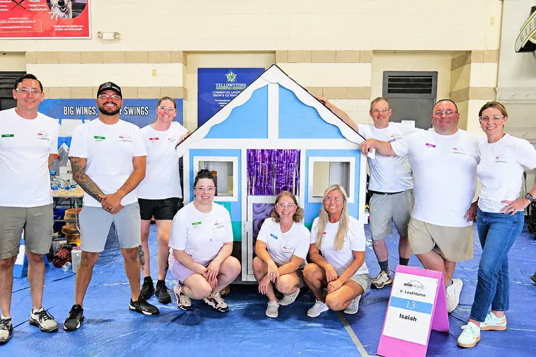 Employees gather around a house-themed project at a community event