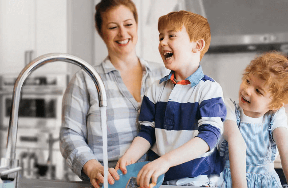 mother with her two children cleaning dishes and smiling together