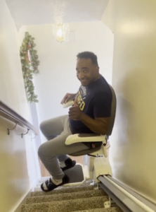 veterans day stair lift winner sits in comfort stairlift going down stairs.